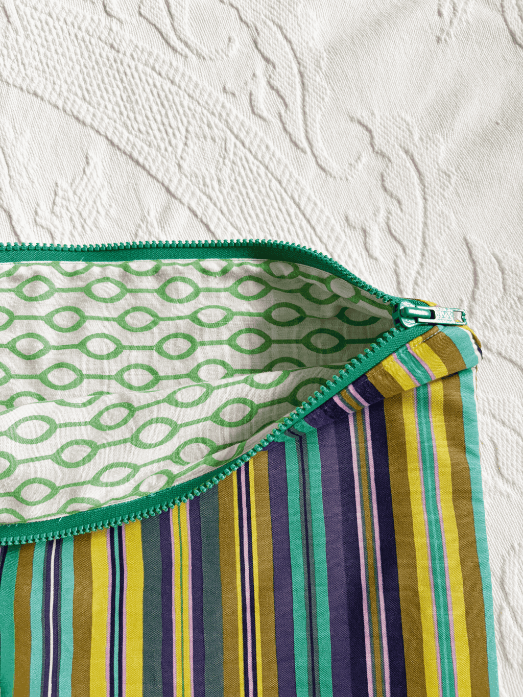 A zippered blue/green striped laptop sleeve with a white and green lining.